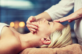 Kobieta ma wykonywany masaż twarzy w salonie SPA