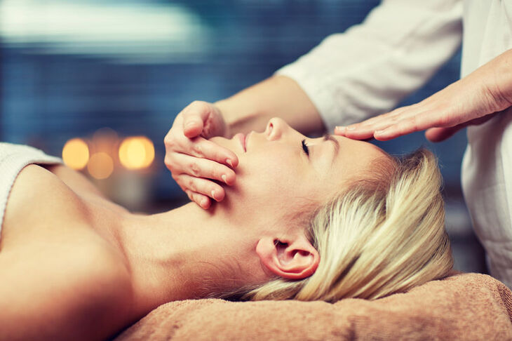 Kobieta ma wykonywany masaż twarzy w salonie SPA