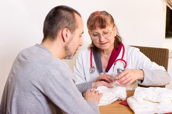 Lekarka pokazuje mężczyźnie wkładki urologiczne na nietrzymanie moczu