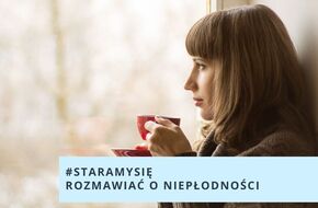 Kobieta stoi przy oknie, trzyma w ręku filiżankę 