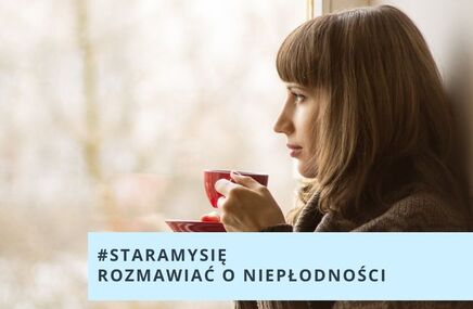 Kobieta stoi przy oknie, trzyma w ręku filiżankę 