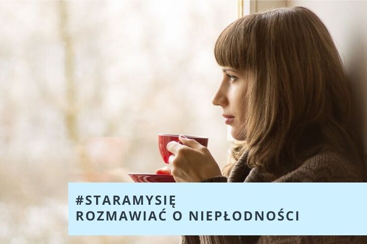 Kobieta stoi przy oknie, trzyma w ręku filiżankę 