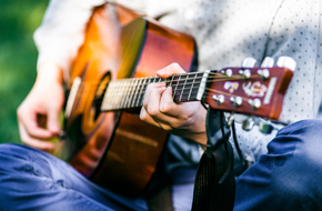 Mężczyzna gra na gitarze korzystając z muzykoterapii
