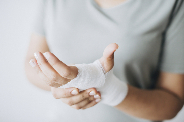 Kobieta z obandażowaną dłonią na której ma zakażoną ranę
