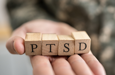 Żołnierz trzyma klocki z litrami na dłoni, które tworzą napis PTSD