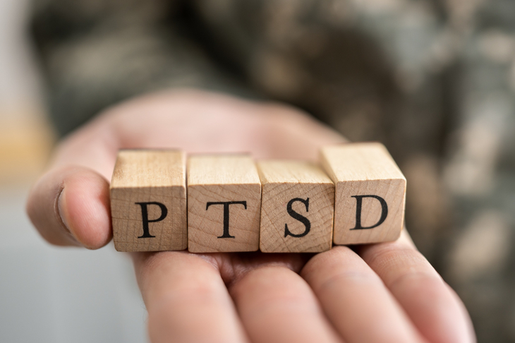 Żołnierz trzyma klocki z litrami na dłoni, które tworzą napis PTSD