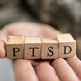 Żołnierz trzyma klocki z litrami na dłoni, które tworzą napis PTSD