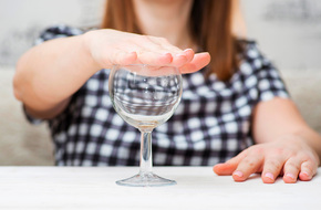 Kobieta zakrywająca kieliszek z alkoholem z powodu uczulenia na alkohol