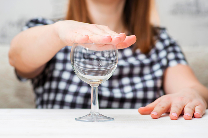 Kobieta zakrywająca kieliszek z alkoholem z powodu uczulenia na alkohol
