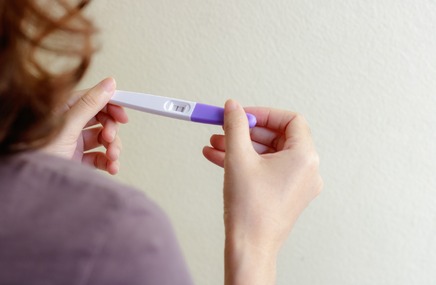 Kobieta w 4 tygodniu ciąży trzyma w dłoniach pozytywny test ciążowy