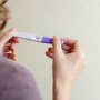 Kobieta w 4 tygodniu ciąży trzyma w dłoniach pozytywny test ciążowy