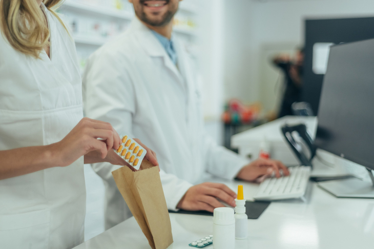 Farmaceuci w aptece pakują witaminy i minerały do suplementacji w neurologii