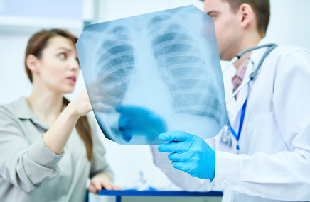 Zdjęcie przedstawia lekarza i pacjentkę omawiających rentgen klatki piersiowej, co może wskazywać na diagnostykę zapalenia opłucnej.
