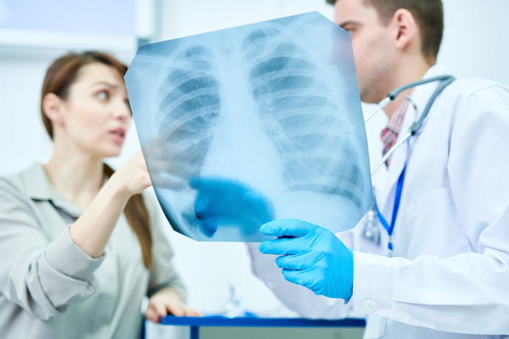 Zdjęcie przedstawia lekarza i pacjentkę omawiających rentgen klatki piersiowej, co może wskazywać na diagnostykę zapalenia opłucnej.