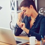 Kobieta siedząca przy laptopie i trzymająca się za zatoki